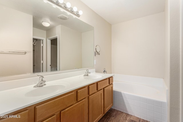 bathroom featuring vanity, tiled tub, and hardwood / wood-style flooring