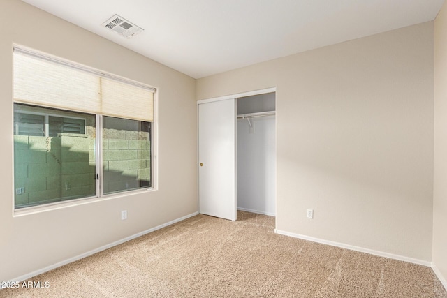 unfurnished bedroom with a closet and light carpet