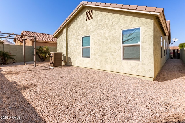 rear view of property featuring a pergola, central AC, and a patio area