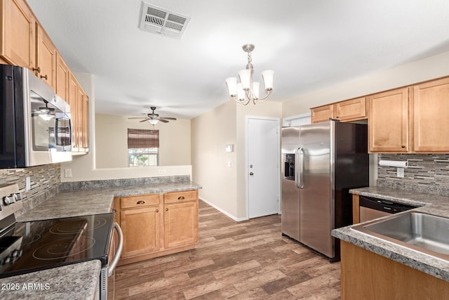 kitchen featuring pendant lighting, hardwood / wood-style flooring, stainless steel appliances, decorative backsplash, and ceiling fan with notable chandelier