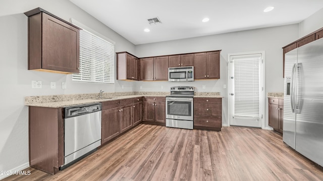 2668 N 73rd Gln, Phoenix, AZ 85035 - kitchen with stainless steel appliances, light wood-style floors, a sink, dark brown cabinetry, and recessed lighting
