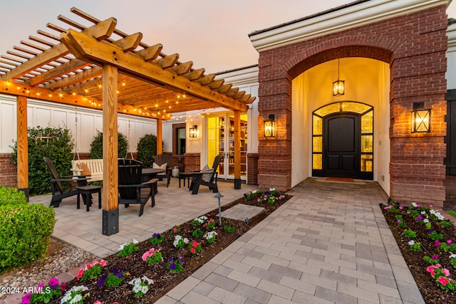 exterior entry at dusk featuring a pergola and a patio