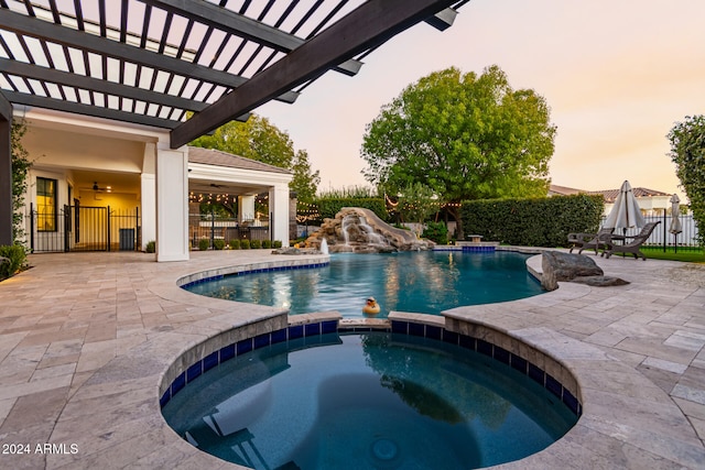 pool at dusk with pool water feature, a pergola, a patio, and an in ground hot tub