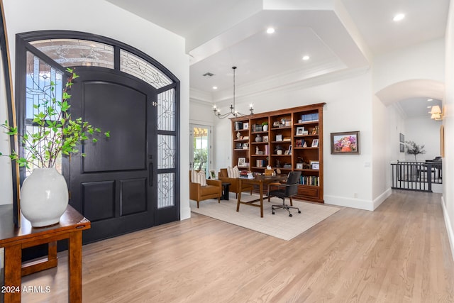 foyer entrance featuring ornamental molding, light wood-type flooring, and a chandelier