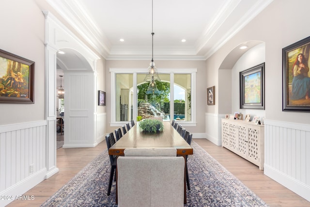 dining area featuring light hardwood / wood-style floors, a raised ceiling, and crown molding