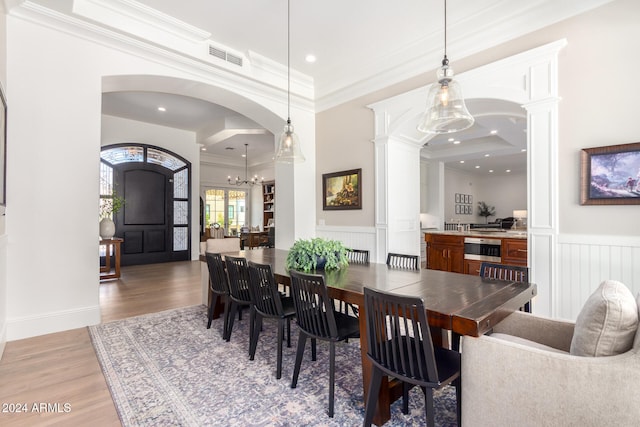 dining area with ornate columns, a chandelier, hardwood / wood-style floors, and ornamental molding