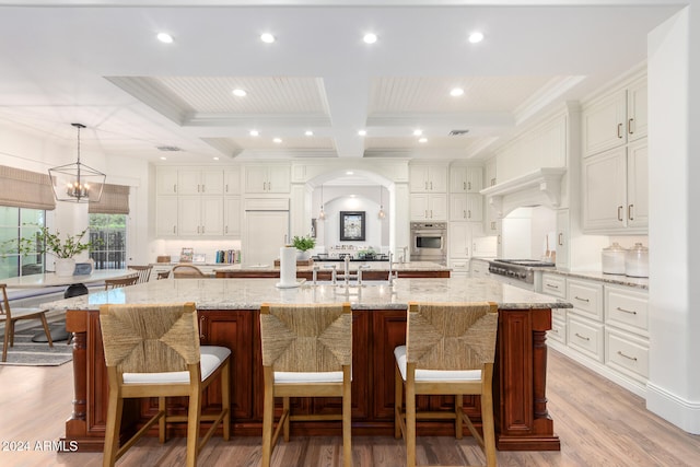 kitchen featuring stainless steel appliances, pendant lighting, a large island, and light hardwood / wood-style flooring