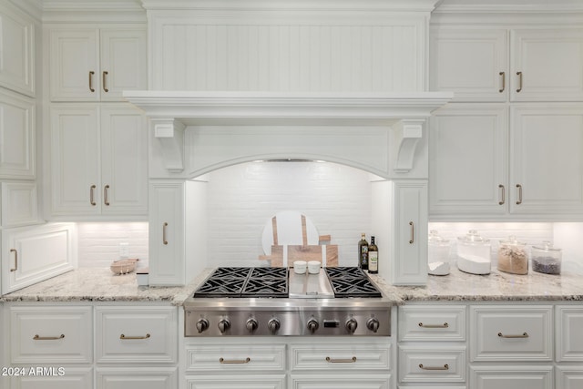 kitchen featuring tasteful backsplash, white cabinetry, stainless steel gas cooktop, and light stone counters