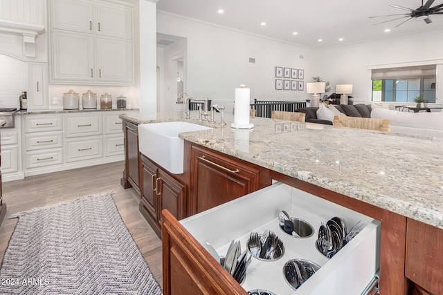 kitchen with sink, ceiling fan, crown molding, white cabinets, and light wood-type flooring