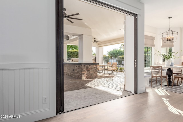 doorway to outside with hardwood / wood-style flooring and ceiling fan with notable chandelier