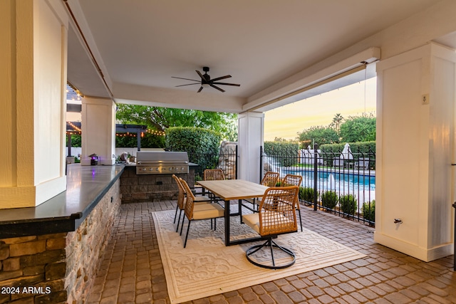 patio terrace at dusk featuring ceiling fan and area for grilling