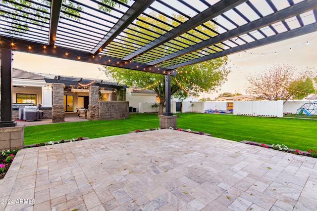 patio terrace at dusk featuring a pergola and a yard