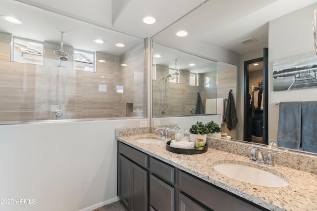 bathroom with a tile shower and vanity