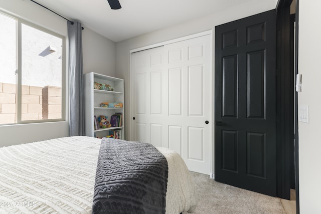 bedroom featuring multiple windows, ceiling fan, a closet, and light carpet