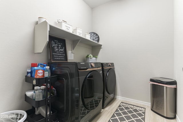 laundry area featuring washing machine and dryer and light hardwood / wood-style flooring