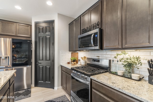 kitchen featuring decorative backsplash, light stone counters, dark brown cabinetry, and stainless steel appliances