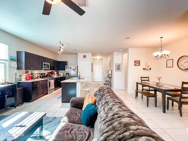 living room featuring ceiling fan with notable chandelier and light tile patterned floors