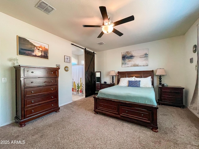 bedroom with ceiling fan, light colored carpet, and a barn door