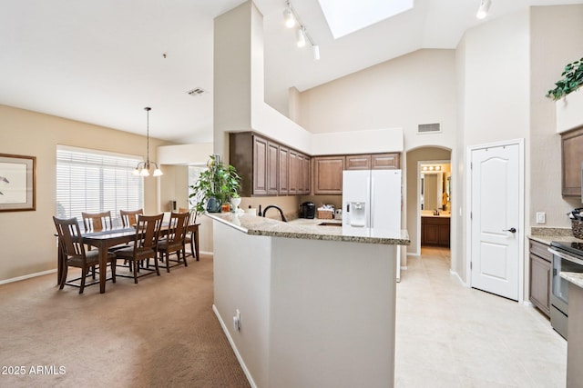 11861 E Becker Ln, Scottsdale, AZ 85259 - kitchen with white refrigerator with ice dispenser, rail lighting, stainless steel electric range, high vaulted ceiling, and light stone counters