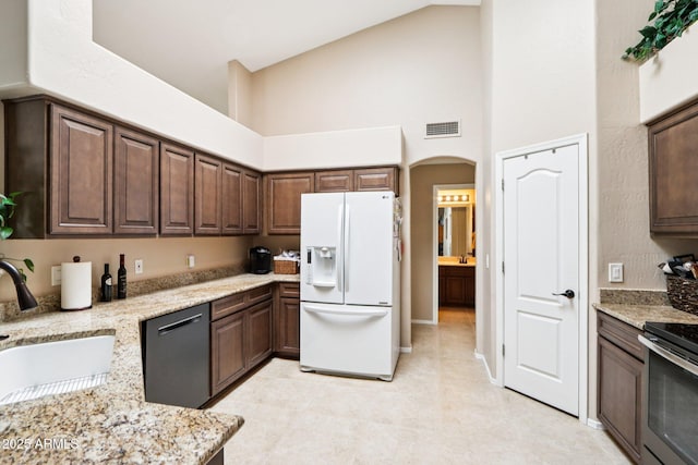 11861 E Becker Ln, Scottsdale, AZ 85259 - kitchen with white fridge with ice dispenser, dishwashing machine, high vaulted ceiling, stainless steel electric range, and light stone countertops