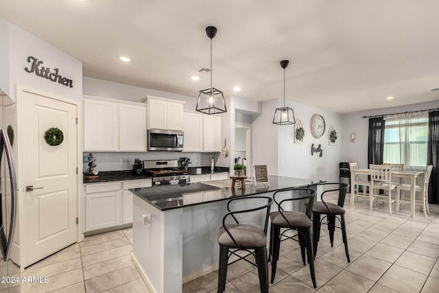 kitchen featuring decorative light fixtures, a center island, white cabinetry, and appliances with stainless steel finishes