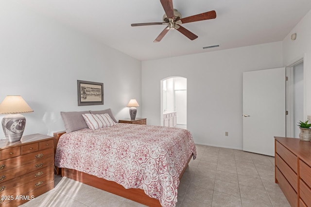 bedroom featuring visible vents, arched walkways, connected bathroom, ceiling fan, and light tile patterned flooring