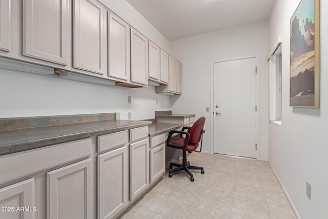 office area with light tile patterned floors, baseboards, and built in study area