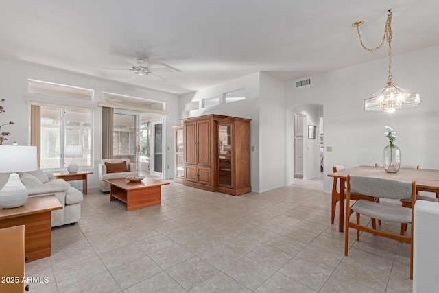 living area featuring baseboards, visible vents, arched walkways, a ceiling fan, and light tile patterned flooring