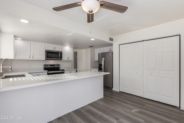 kitchen with dark wood-type flooring, white cabinets, sink, kitchen peninsula, and stainless steel appliances