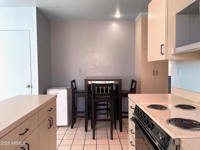 kitchen with light tile patterned flooring, fridge, and electric stove