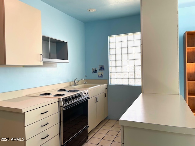 kitchen featuring a wealth of natural light, white cabinetry, electric stove, sink, and light tile patterned floors