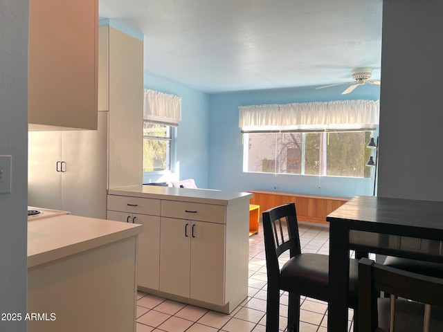 kitchen featuring ceiling fan, white cabinets, light tile patterned flooring, and a center island