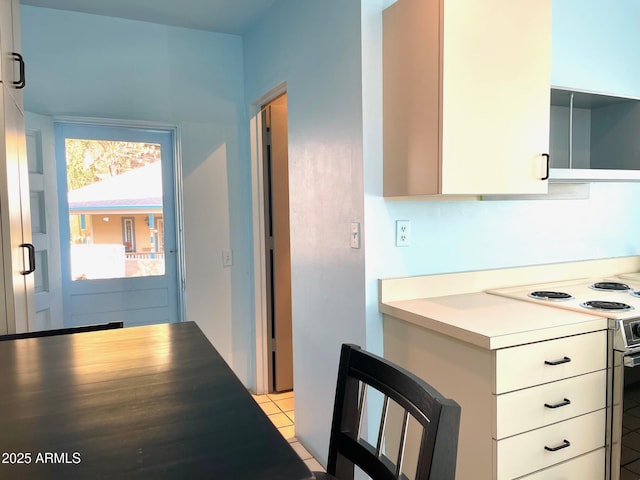 kitchen with light tile patterned floors, white cabinets, and range with electric cooktop