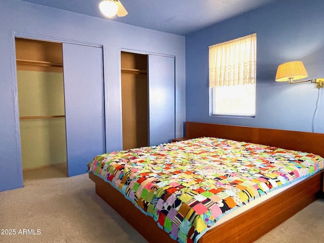 carpeted bedroom featuring ceiling fan and two closets