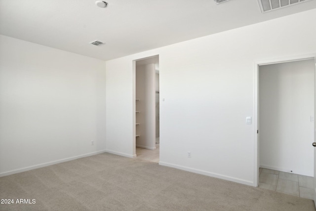 unfurnished room featuring baseboards, visible vents, and light colored carpet