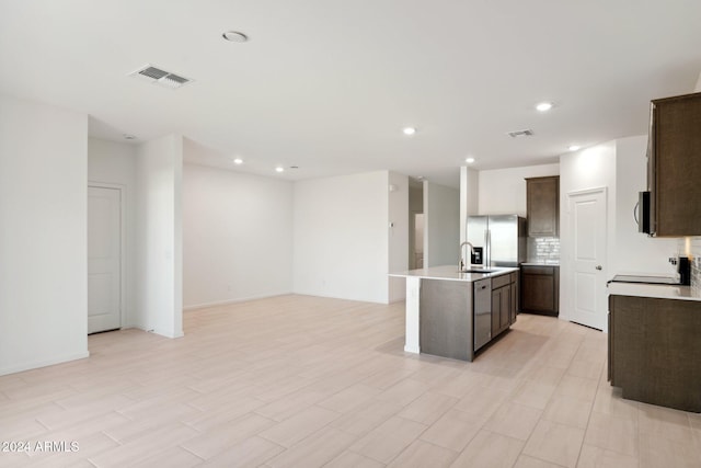 kitchen with light countertops, an island with sink, visible vents, and stainless steel appliances