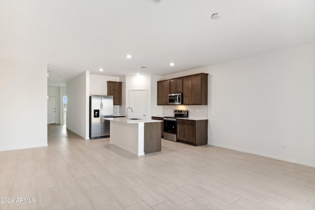 kitchen featuring a center island with sink, stainless steel appliances, recessed lighting, light countertops, and backsplash