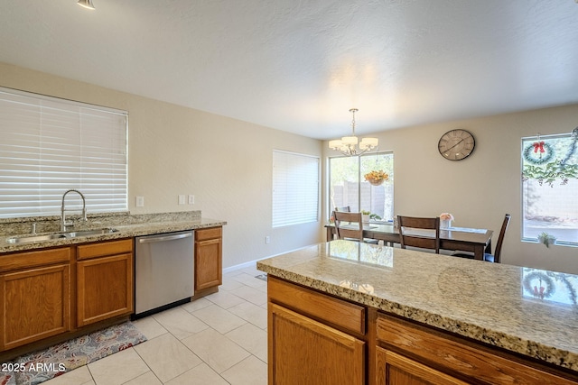 kitchen with sink, hanging light fixtures, light stone counters, light tile patterned floors, and stainless steel dishwasher