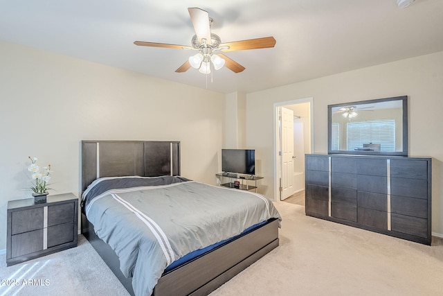 bedroom with ceiling fan, light colored carpet, and ensuite bath