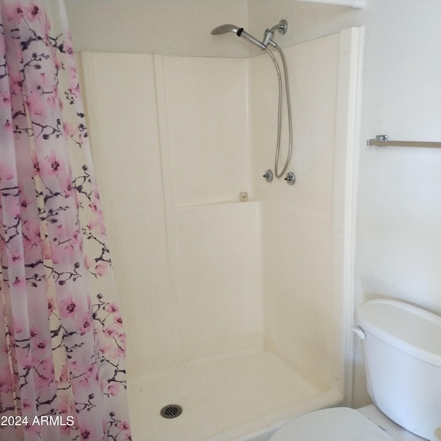 bathroom featuring toilet and curtained shower