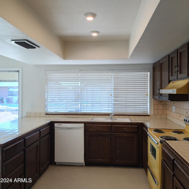 kitchen with dark brown cabinets, tile counters, sink, white dishwasher, and range with electric stovetop