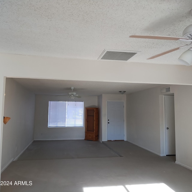 unfurnished room with concrete flooring, ceiling fan, and a textured ceiling