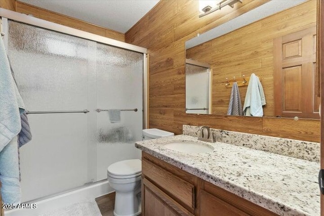 bathroom with toilet, wood walls, vanity, and an enclosed shower