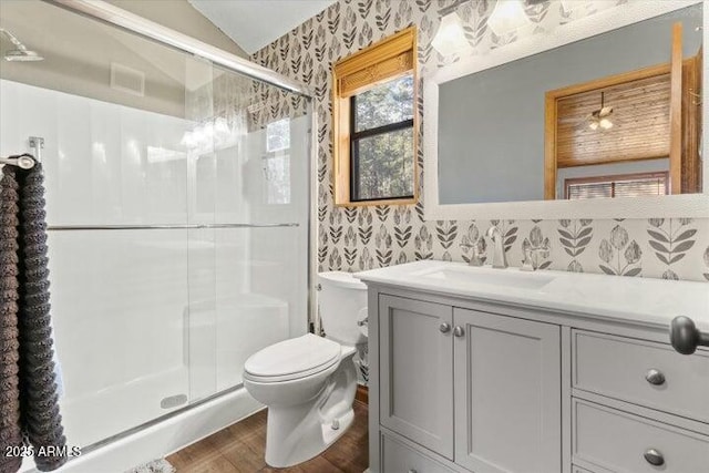 bathroom with toilet, a shower with shower door, wood-type flooring, vaulted ceiling, and vanity