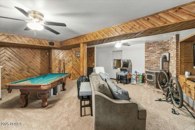 game room with carpet, billiards, ceiling fan, wooden walls, and a wood stove