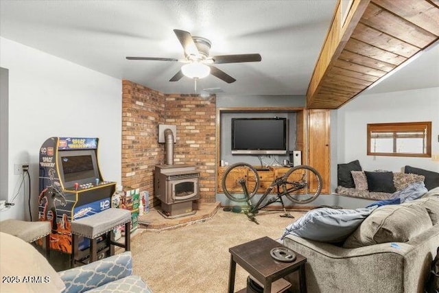 living room featuring carpet, ceiling fan, and a wood stove