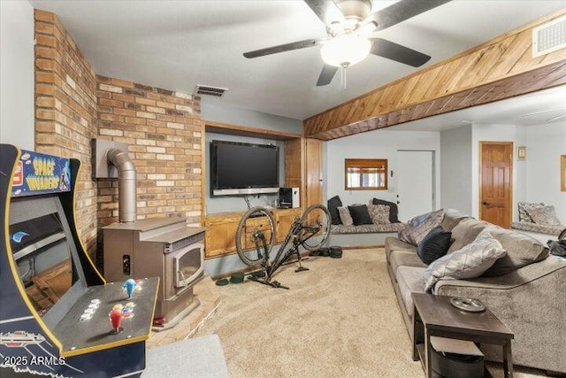 living room featuring ceiling fan, a wood stove, and light colored carpet