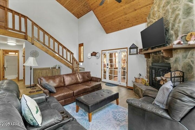 living room featuring ceiling fan, a fireplace, light hardwood / wood-style flooring, high vaulted ceiling, and wooden ceiling