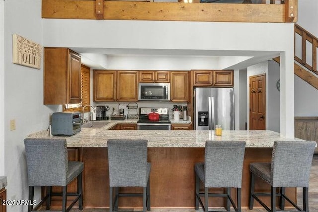 kitchen with a kitchen breakfast bar, light stone countertops, appliances with stainless steel finishes, and sink