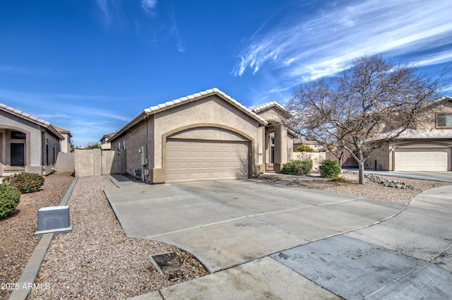 view of front of home with driveway, a garage, a tile roof, fence, and stucco siding